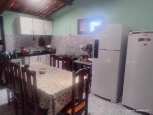 a kitchen with a table and a white refrigerator at hostel xamã in Flecheiras