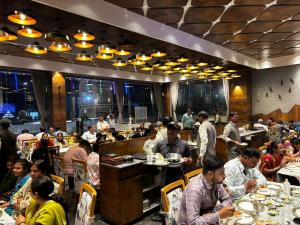 a group of people sitting at tables in a restaurant at HOTEL SILVERA GRAND in Ahmedabad