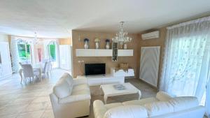 a living room with white couches and a tv at Villa singola con piscina Quinta Est in Rosolina
