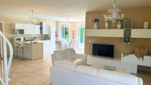 a living room with a white couch and a kitchen at Villa singola con piscina Quinta Est in Rosolina