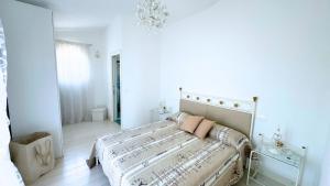 a white bedroom with a bed and a chandelier at Villa singola con piscina Quinta Est in Rosolina +14 photos