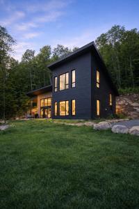 a black house with lights on in a yard at Havre du Mont in Saint Come