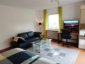 a living room with a couch and a table and a television at Vogelparadies Homestay Nichtraucher in Hemhofen