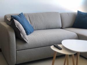 a gray couch with blue pillows and a white table at Refugio climático en Finisterre frente a la playa con vistas al mar!! in Fisterra