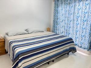 a bedroom with a bed with a blue and white blanket at Departamento Arena- Oasis del Mar in Progreso +7 photos