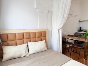a bed with white pillows and a desk in a room at Four P Home and Studio in Ho Chi Minh City