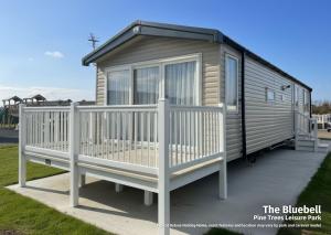 a tiny house with a white fence on a deck at Pine Trees Leisure Park in Skegness