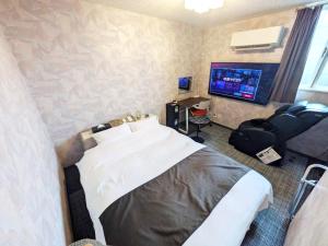 a hotel room with a bed and a flat screen tv at セルフプラスホテル銚子無人ホテル in Choshi