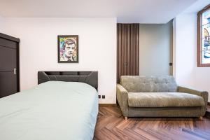 a bedroom with a bed and a chair at Le Belmondo Grand Studio in Moutiers