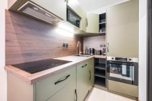 a kitchen with white cabinets and a stove top oven at Le Belmondo Grand Studio in Moutiers