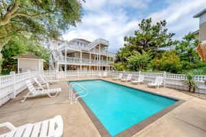 a swimming pool with chairs and a house at The Nauti Flyer in Corolla