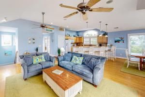 a living room with two couches and a table at The Nauti Flyer in Corolla