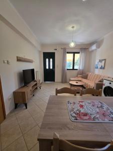 a living room with a couch and a tv at Christos Sunhaven Apartment in Agia Ermioni