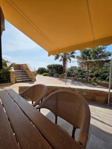 a wooden table and chairs under a yellow umbrella at Christos Sunhaven Apartment in Agia Ermioni