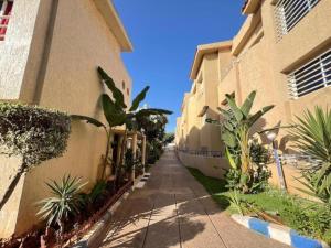 a walkway between two buildings with palm trees at Spacious Triplex in Harhoura in El Harhoura