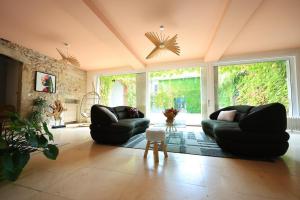 a living room with black couches and a large window at Bégous in Valderiès