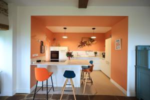 a kitchen with orange walls and orange stools at Bégous in Valderiès