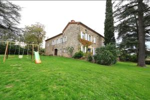 an old stone building with a playground in a yard at Bégous in Valderiès