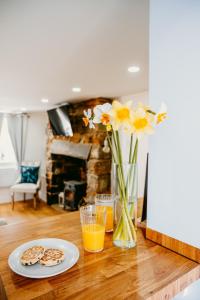 a table with a vase of flowers and two glasses of orange juice at Pauls Place in Brynsiencyn