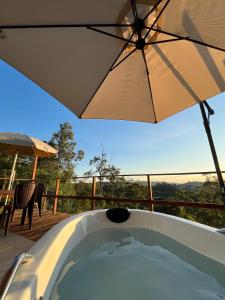 a hot tub with an umbrella on a deck at Cabana da Lua Chalés Vero Verde in Serra Negra +26 photos
