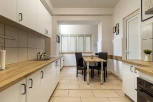 a kitchen with white cabinets and a wooden table at Schiller Apartment - Old Town in Sibiu
