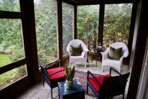 a screened in porch with chairs and a table at The Little Inn in Bayfield