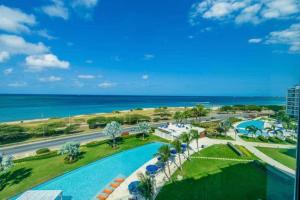 an aerial view of a resort with a swimming pool and the ocean at Glamorous and modern beach apartment Eagle beach ARUBA in Savaneta