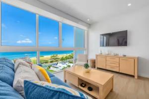 a living room with a blue couch and a large window at Glamorous and modern beach apartment Eagle beach ARUBA in Savaneta