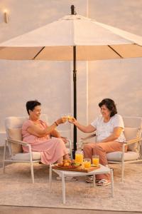 two women sitting in chairs under an umbrella at Altitud 620 Boutique Suites in Nazca