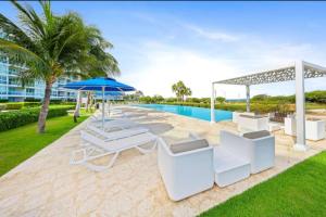 a patio with chairs and an umbrella and a pool at Glamorous and modern beach apartment Eagle beach ARUBA in Savaneta