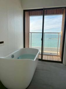 a white bath tub in a bathroom with a view of the ocean at Laina Kai in Sumoto +43 photos