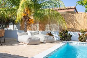 a swimming pool with two beds next to a palm tree at Villa CuraSol in Jan Thiel
