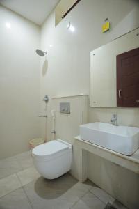 a bathroom with a white toilet and a sink at LK.Lodge in Kanyakumari +2 photos