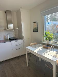 a white kitchen with a table and a window at Tunneberga 1 65 in Jonstorp