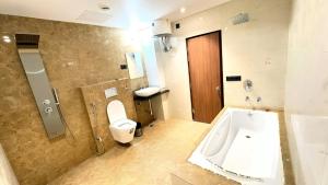 a bathroom with a tub and a toilet and a sink at Hotel Parv Vilas in Behror