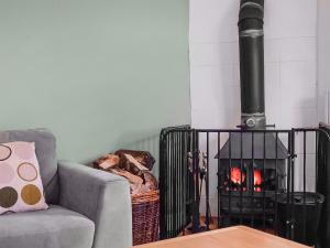 a fireplace in a living room with a couch and a fire place at Stream Cottage - 27550 in Wheddon Cross