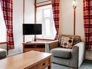 a living room with a chair and a tv at Stream Cottage - 27550 in Wheddon Cross
