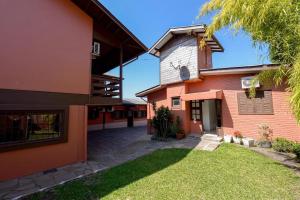 a house with a grass yard next to a building at Pousada Prime Gramado in Gramado