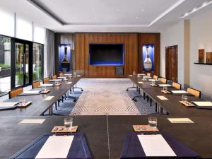 ein Konferenzraum mit langen Tischen und einem großen Bildschirm in der Unterkunft Movenpick Hotel Abidjan in Abidjan