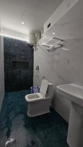 a bathroom with a white toilet and a sink at Sunrise Inn in Yelagiri