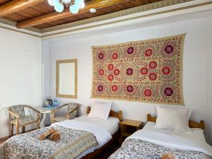 two beds in a room with a painting on the wall at Samani Bukhara in Bukhara