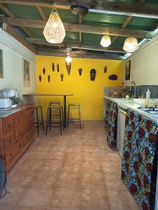 a kitchen with a table and a yellow wall at Ma chambre Javanaise in Port-Louis