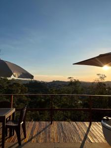 a deck with a table and chairs and an umbrella at Cabana do sol Chalés Vero Verde in Serra Negra