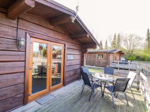 a wooden cabin with a table and chairs on a deck at Primrose Lodge in Evesham