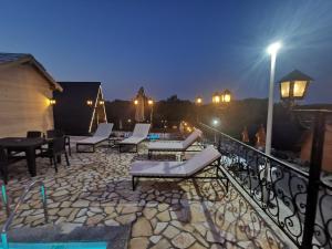 a patio with chairs and a table on a balcony at night at Koliba Buba in Brčko