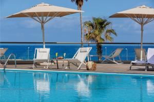a swimming pool with chairs and umbrellas and the ocean at InterContinental David Tel Aviv by IHG in Tel Aviv