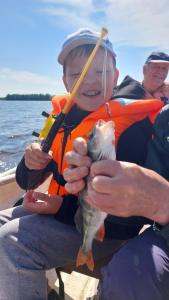 Ein Mann hält auf einem Boot einen Fisch in den Händen in der Unterkunft Pohja in Joensuu + 3 Fotos