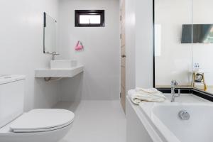 a white bathroom with a toilet and a bath tub at Deluxe Hotel Chaiyaphum in Chaiyaphum