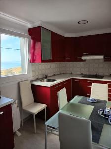 a kitchen with red cabinets and a table and a window at O Chaleco in San Ciprián