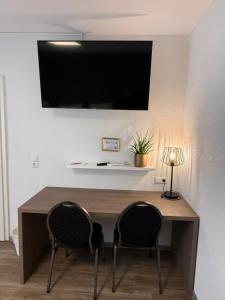 a desk with two chairs and a television on a wall at CityApartment K1 KLIMATISIERT in Friedrichshafen